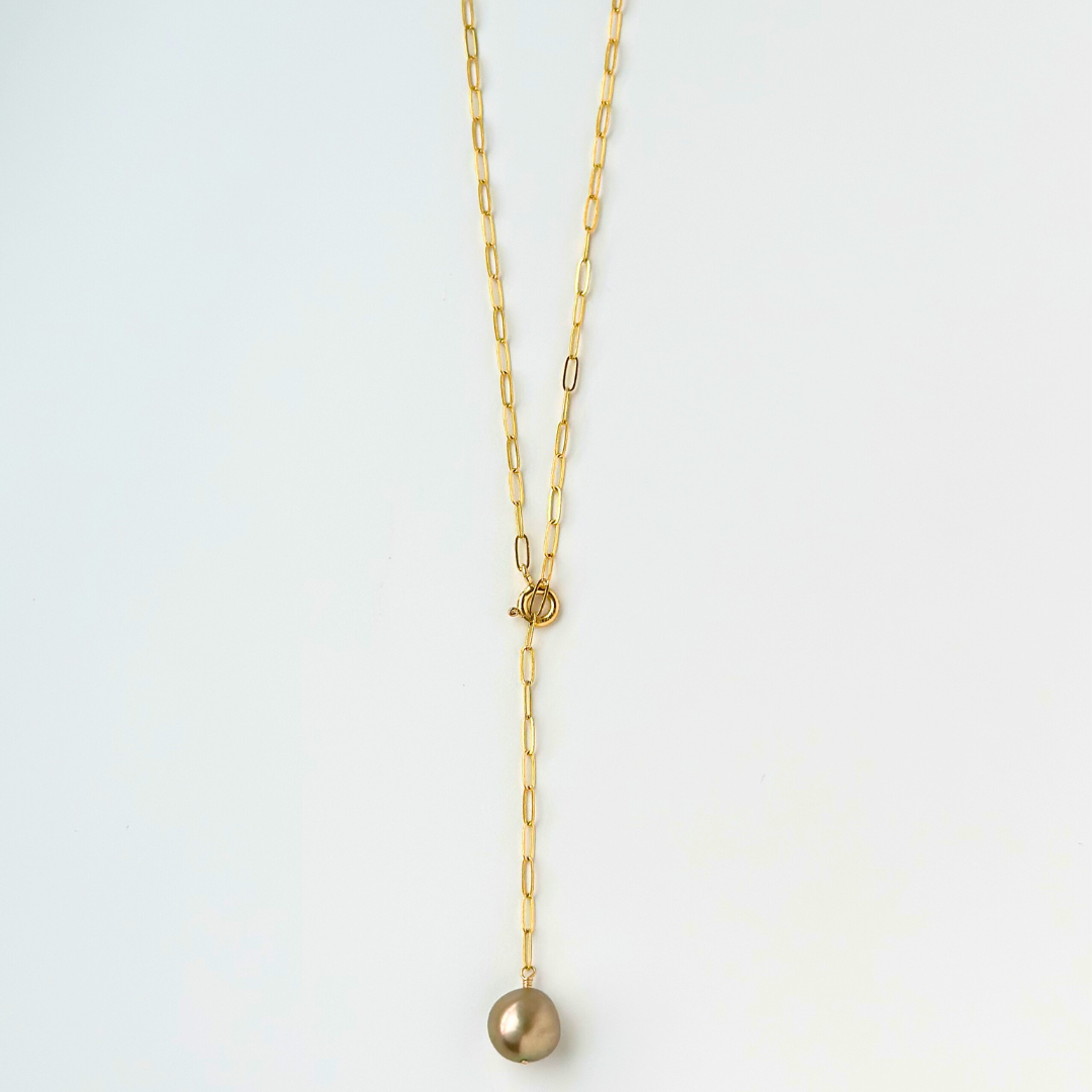 Gold necklace with a single pearl pendant on a light gray background