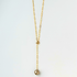 Gold necklace with a single pearl pendant on a light gray background