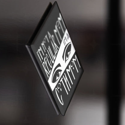 Side profile of the goth mom fridge magnet showing depth and glossy surface, attached to dark metallic surface