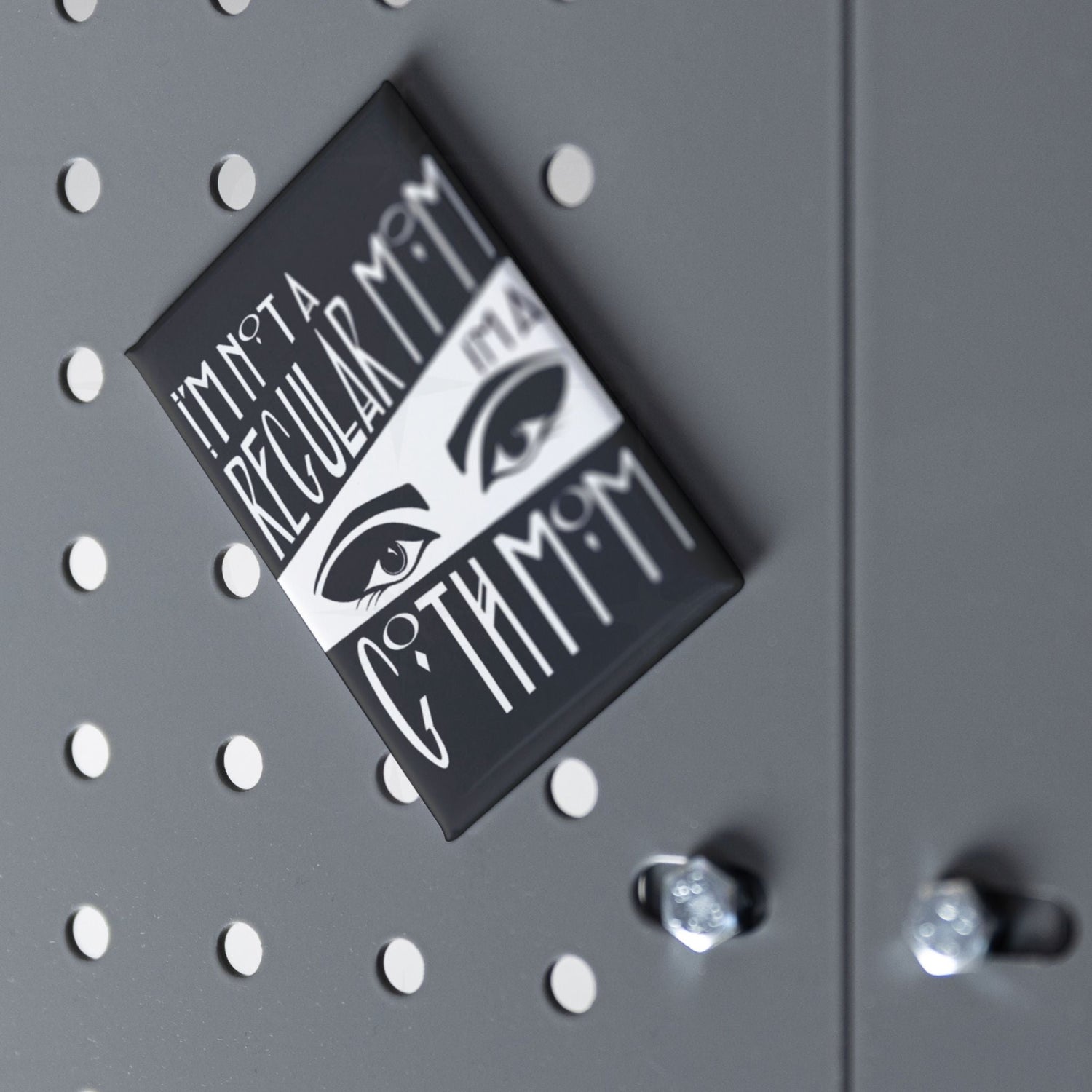 Goth mom fridge magnet displayed at an angle on a grey pegboard surface with chrome hardware visible