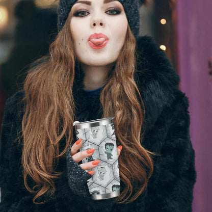 Woman in a black fur coat and beanie holding the green and plum chibi monster tumbler on a city street
