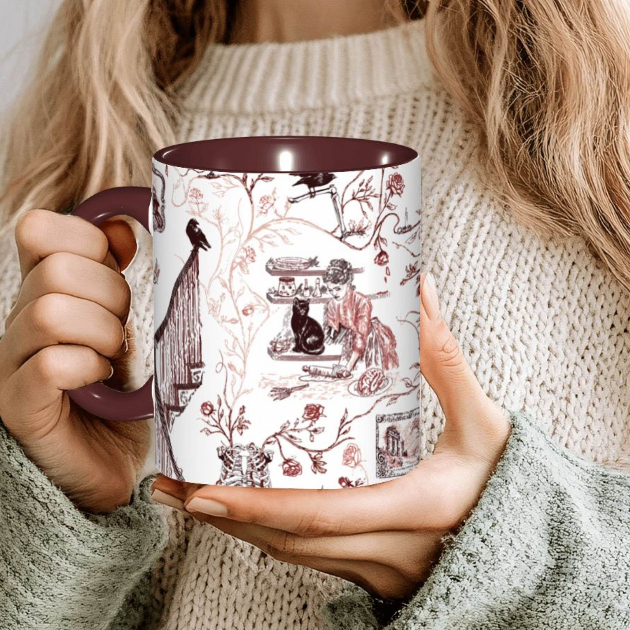 Person holding an oxblood red Victorian zombie toile mug with a maroon interior
