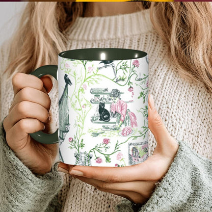 Person holding a forest green preppy gothic toile zombie mug with pink roses and a black cat