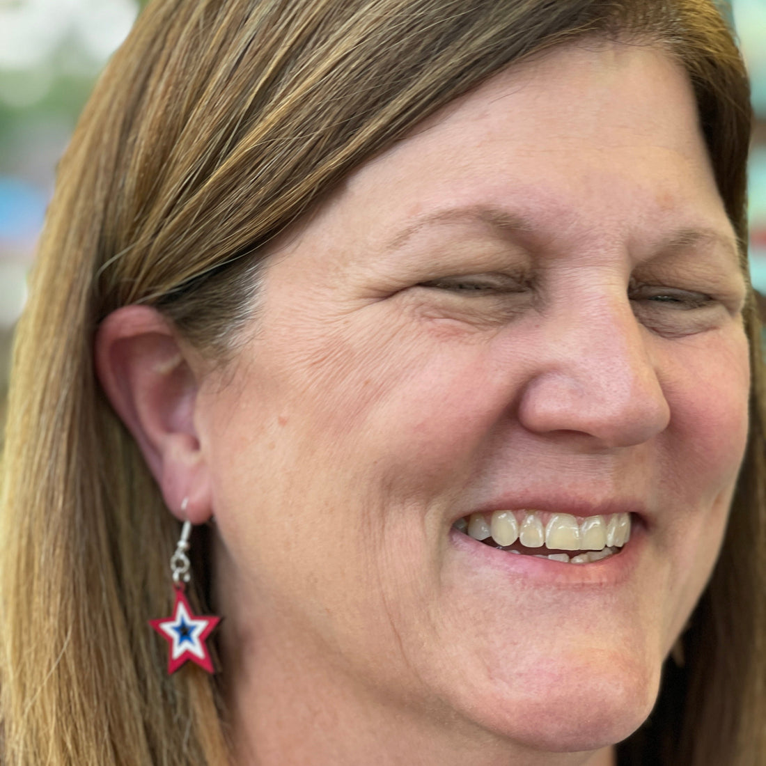 Person wearing hand-painted patriotic star wooden dangle earring on a hypoallergenic .925 sterling silver hook, showing the lightweight size and fit when worn. Red, white, and blue star jewelry perfect for patriotic celebrations, Independence Day, Memorial Day, and everyday American pride.