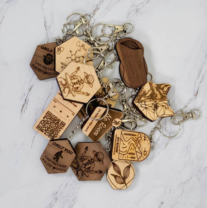 The caffeine molecule wooden keychain shown with the wider PRWMade wooden keychain collection in maple and walnut, for scale and wood comparison