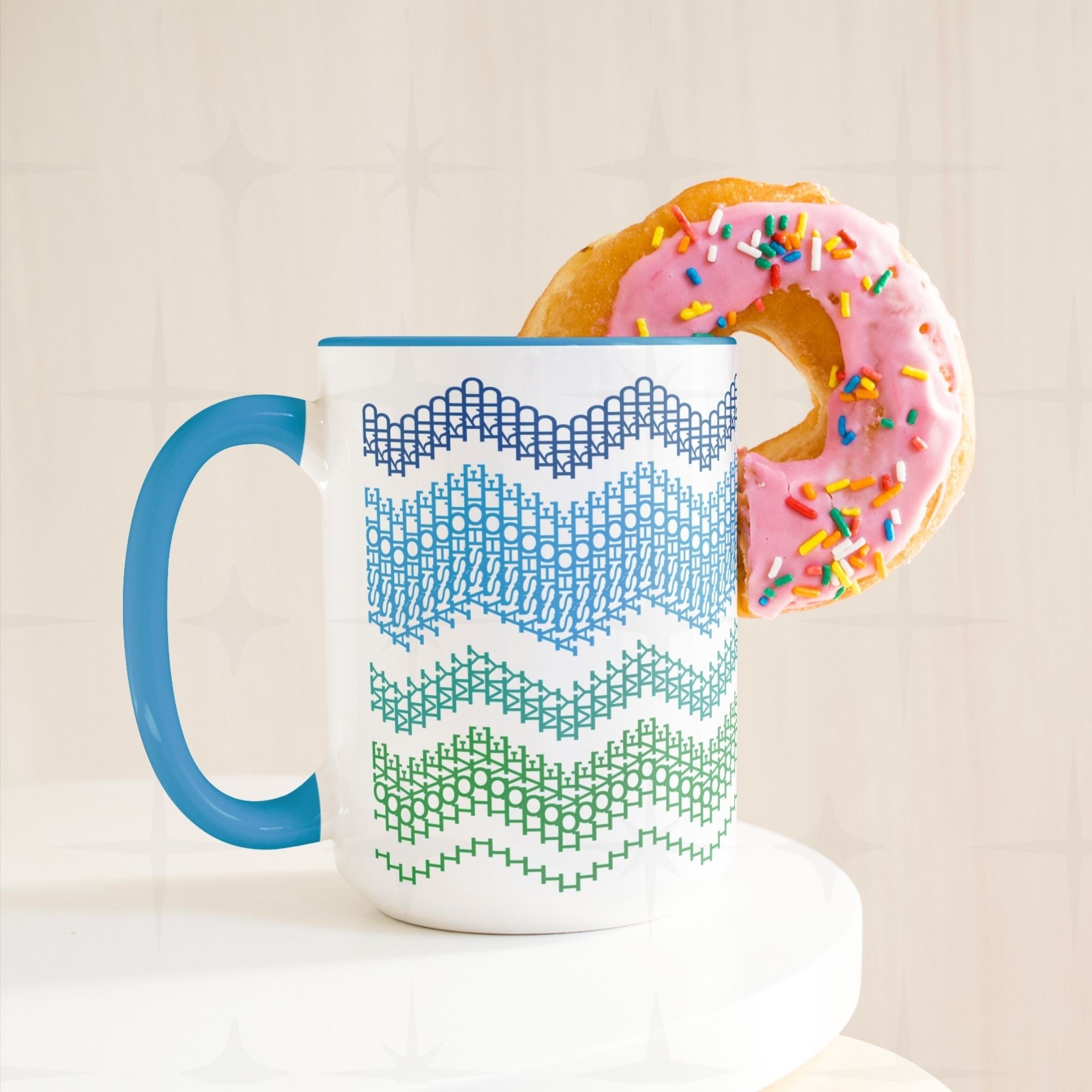 Lifestyle product shot of the Ocean Blue 15oz hidden message mug on a white surface with a pink sprinkle donut resting on the rim