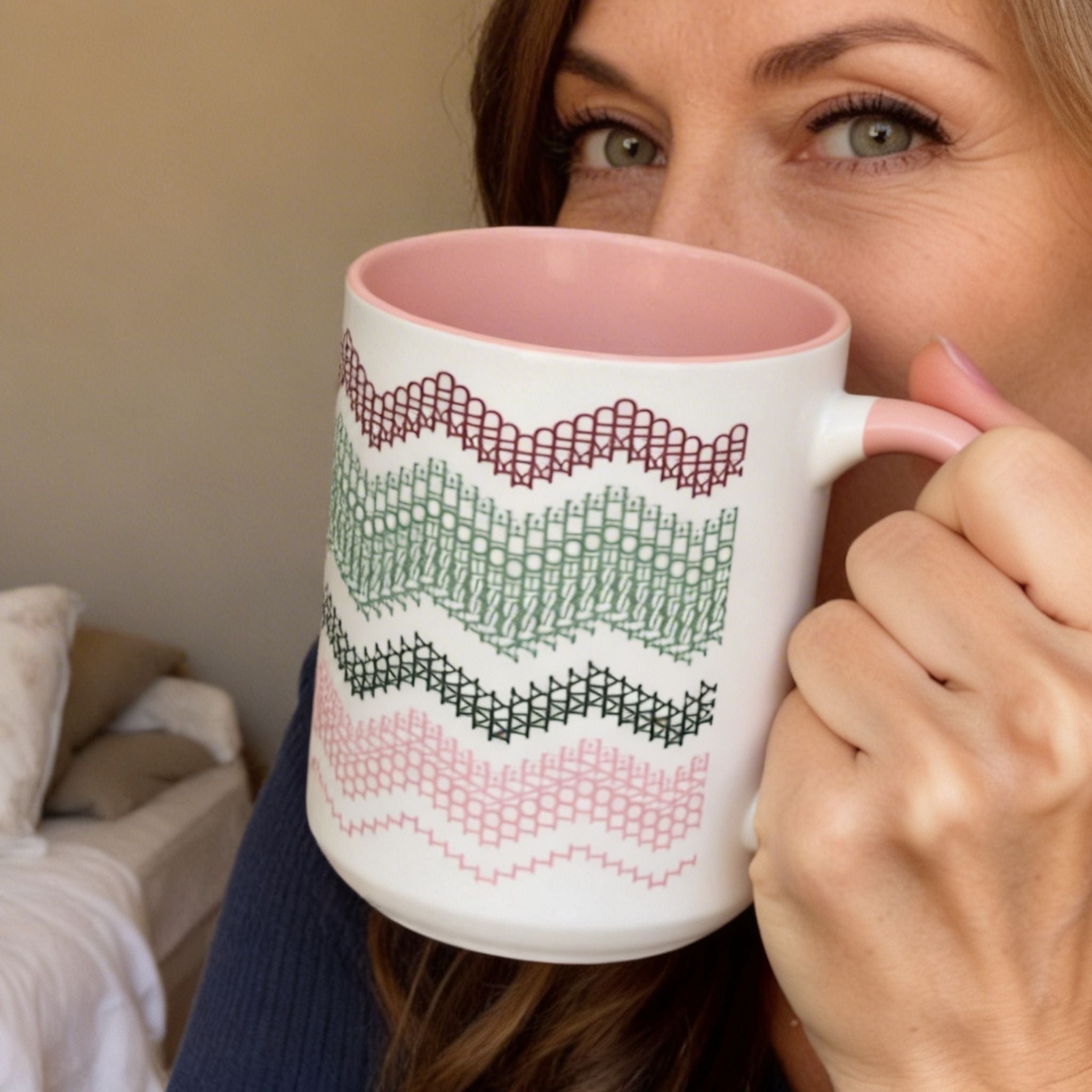 Lifestyle close-up of a woman with green eyes holding the Preppy Pink 15oz hidden message mug near her face, looking over the rim