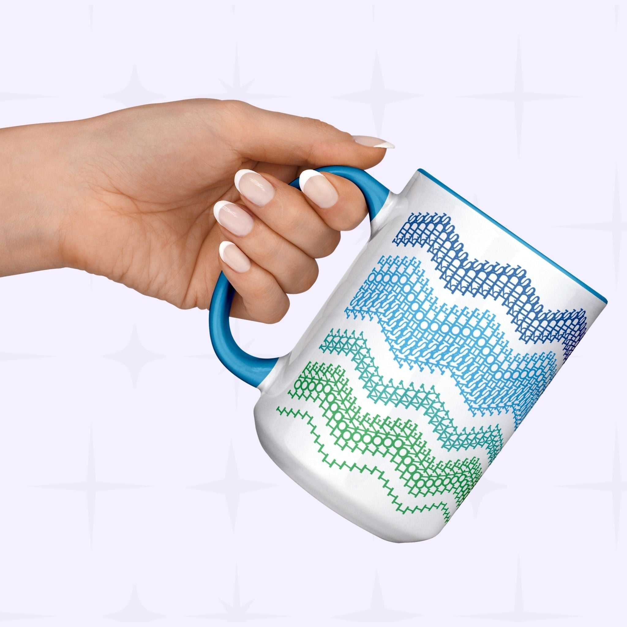Hand holding Ocean &amp; Blue hidden message mug by its blue handle against a light lavender background — showing the navy-to-green typographic fair isle wave pattern