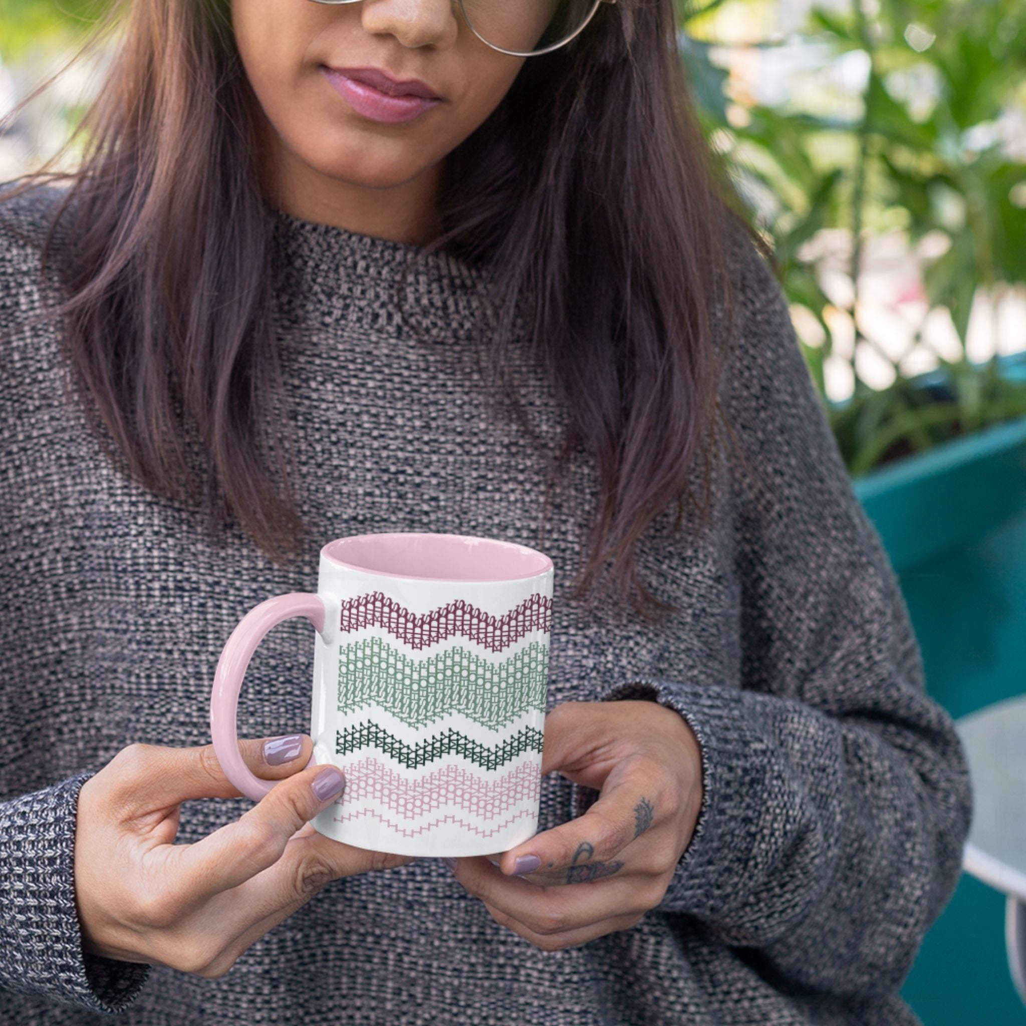 Preppy &amp; Pink hidden message mug 11oz held in both hands outdoors with green plants in background — showing the full burgundy, sage, forest green, and pink typographic pattern