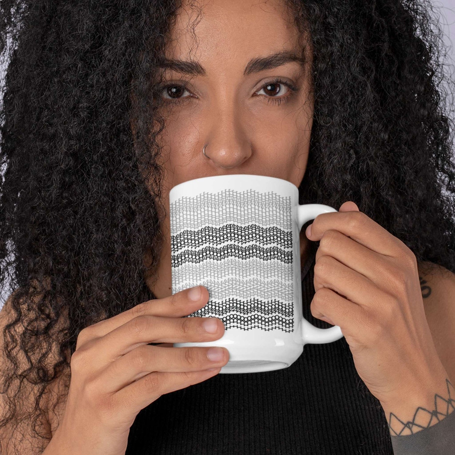 Woman with curly hair holding gray stripes hidden message embroidery mug in front of face