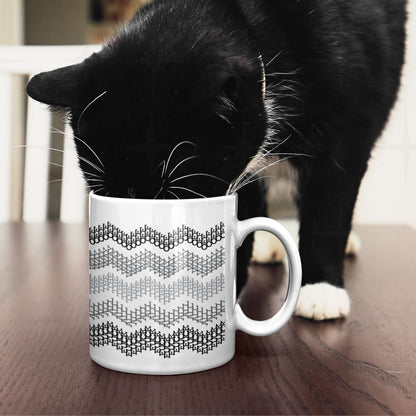 Black and white tuxedo cat investigating gray stripes hidden profanity chevron mug on dark wood table