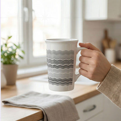 Hand holding gray stripes hidden profanity latte mug in bright kitchen, knit stitch text pattern in light gray to charcoal on white ceramic
