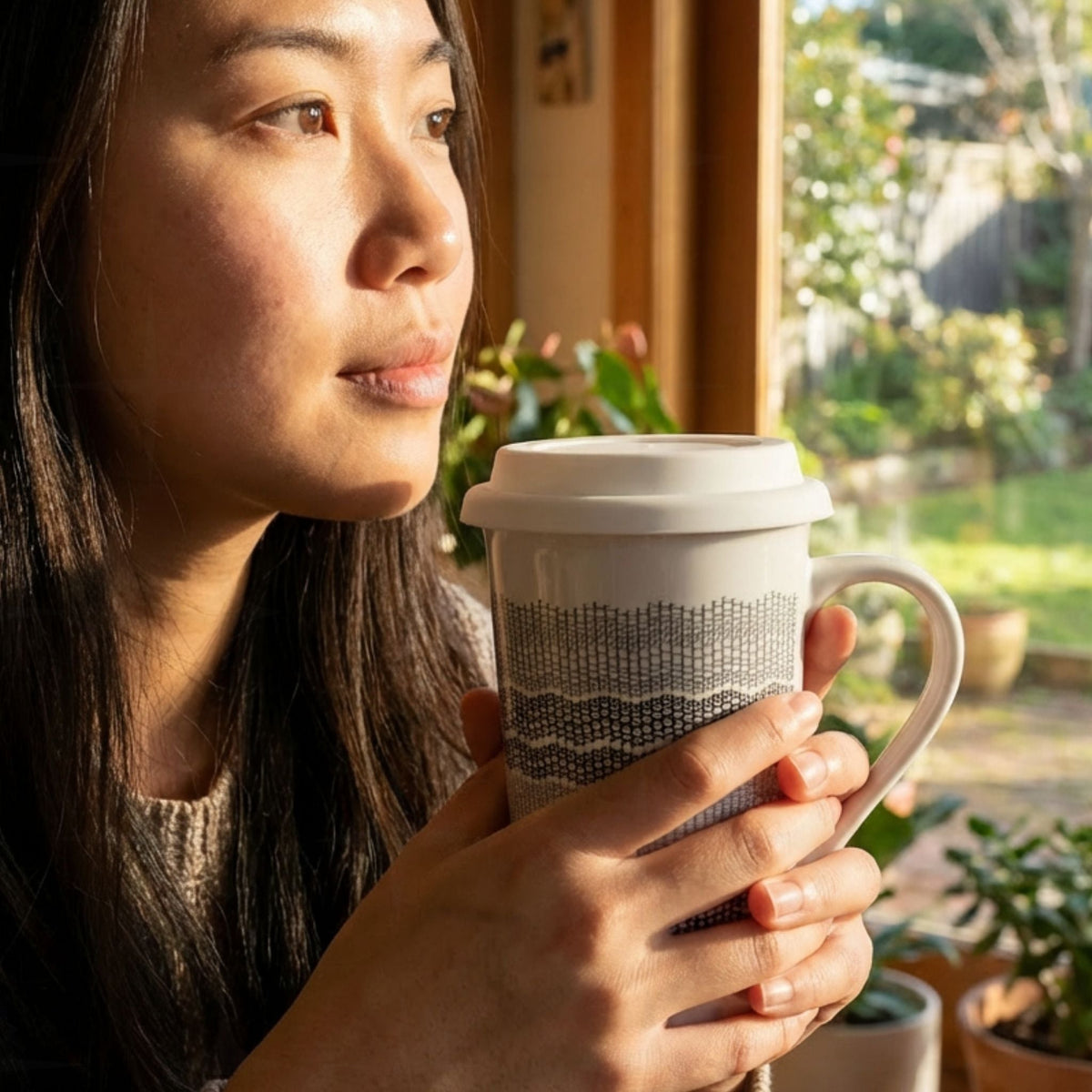 Woman holding gray stripes hidden profanity latte mug by a sunny window, charcoal ombre knit stitch pattern on white ceramic