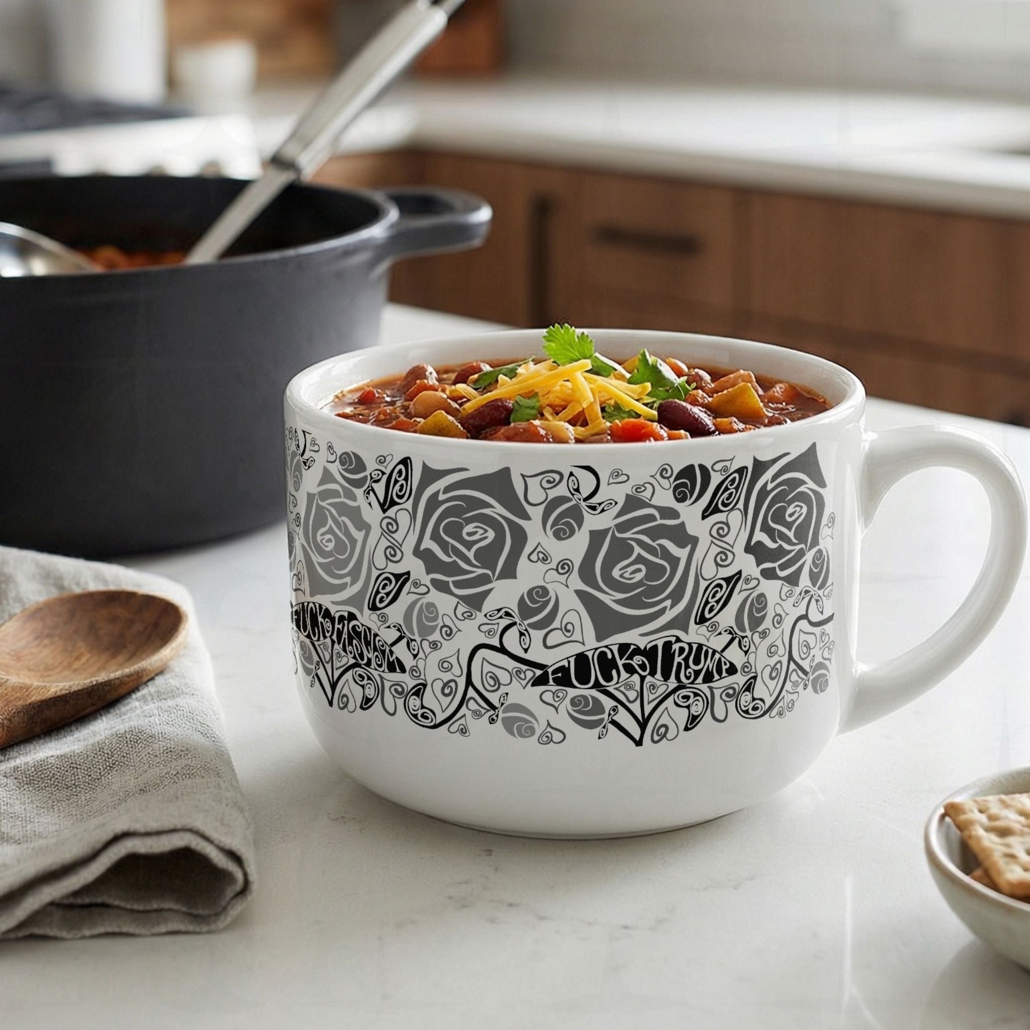 Hidden profanity 25oz latte mug filled with chili on white countertop, black and gray rose pattern with protest text banners visible on white ceramic

