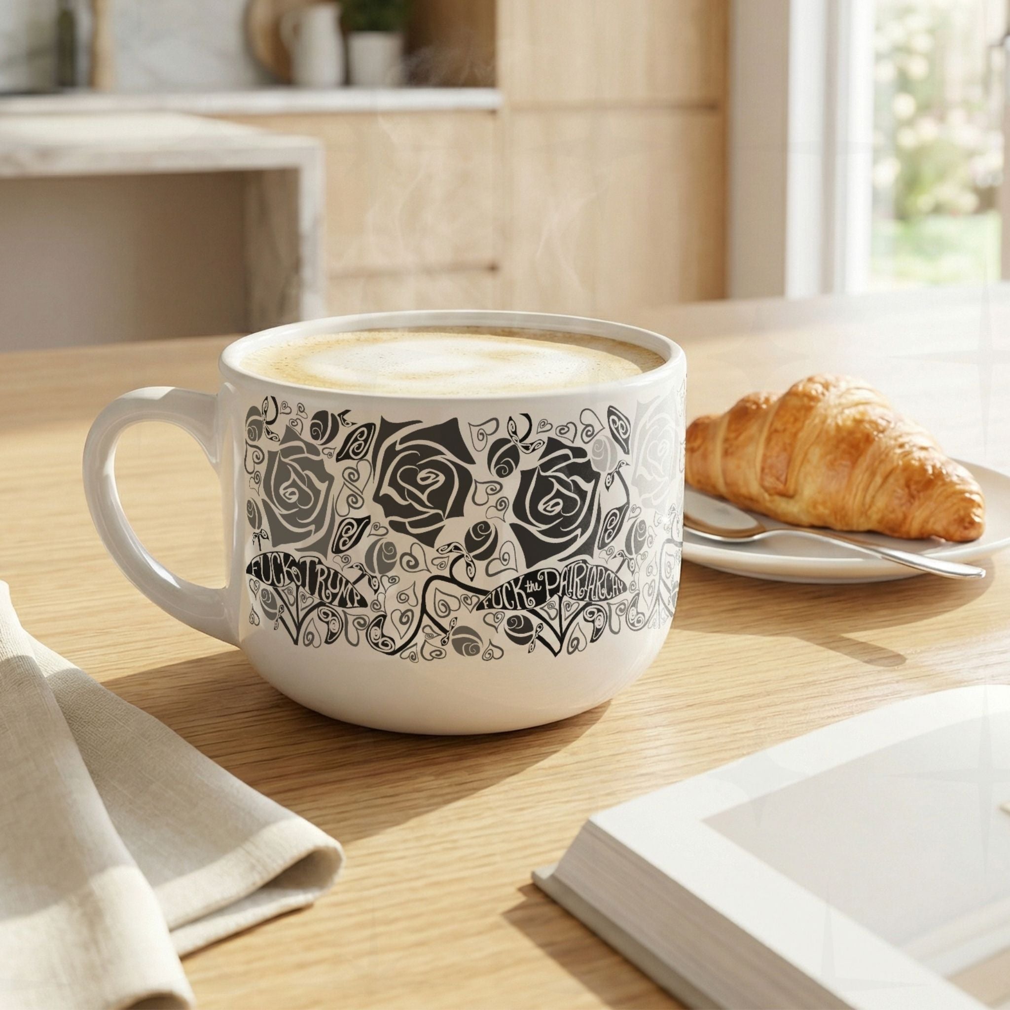 Hidden profanity latte mug with steaming latte on wooden kitchen counter, monochrome gothic rose pattern with hand-lettered political protest banners visible, croissant alongside