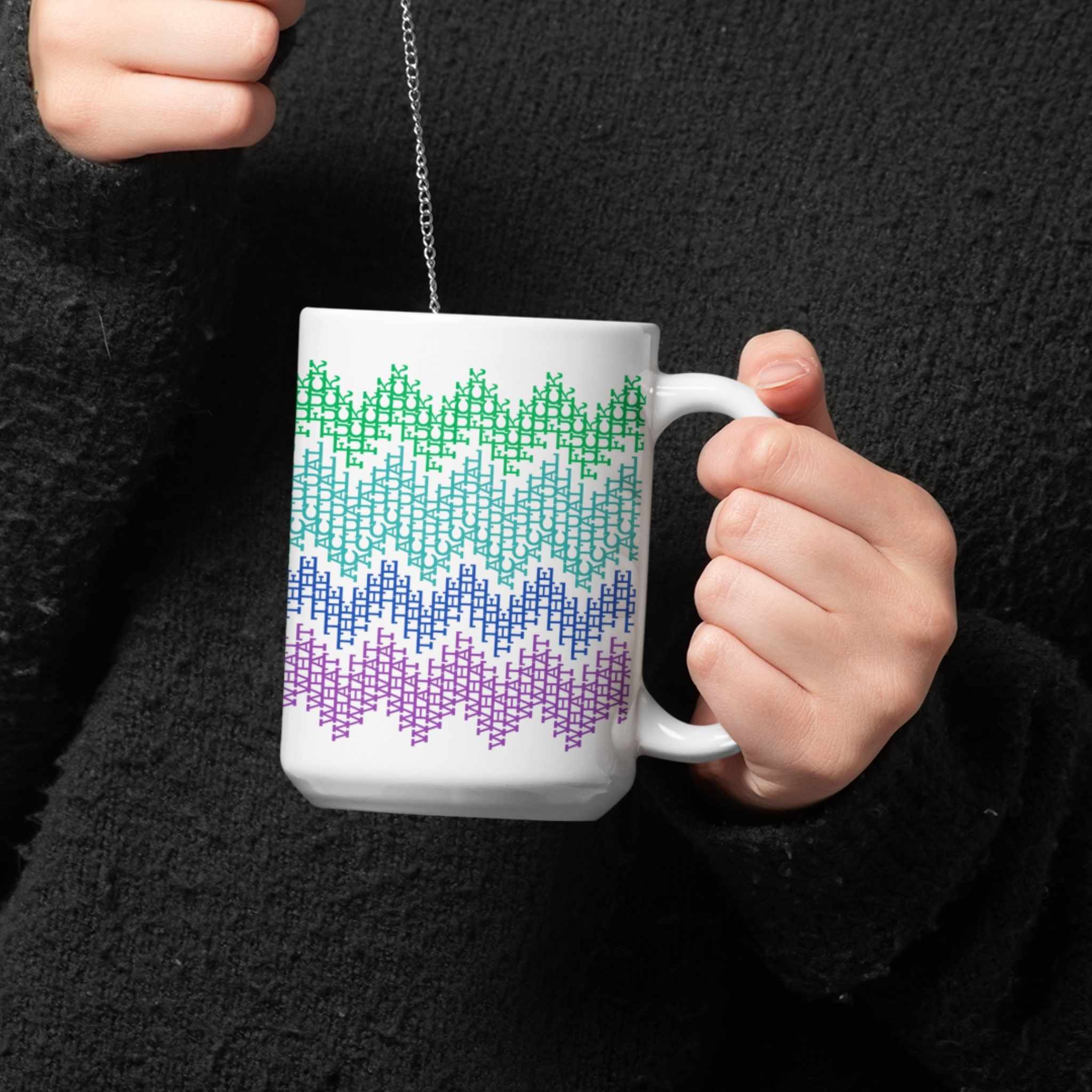 Woman in black sweater cradling a colorful hidden profanity coffee mug against her chest with a pendant necklace visible