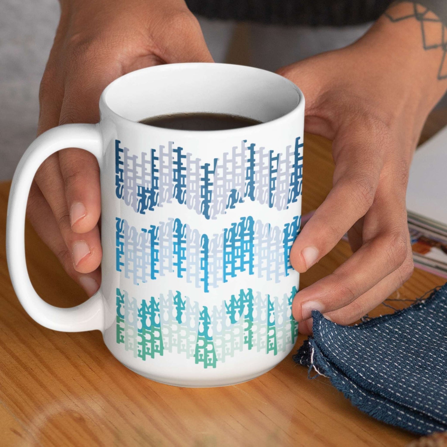 Person holding 15oz hidden profanity coffee mug with ocean ombre typographic chevron design filled with black coffee
