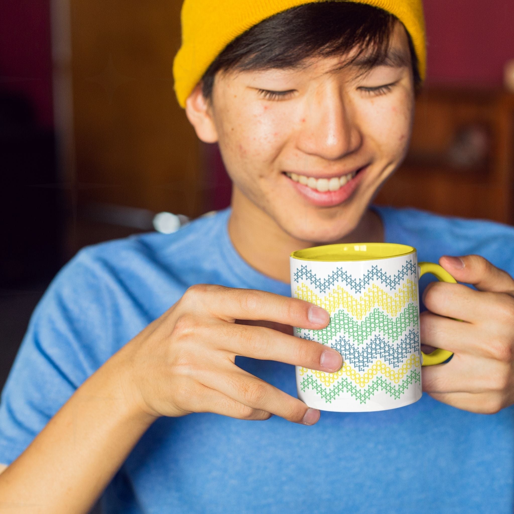 Person smiling while reading hidden message on Go Fuck Yourself cross stitch coffee mug with yellow accent handle