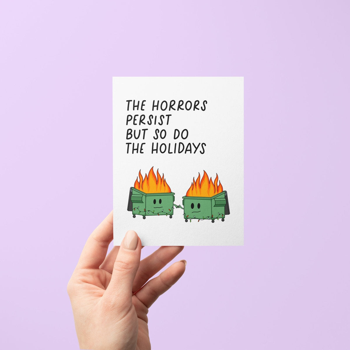 Horrors Persist But So Do the Holidays card flat lay — dark humor dumpster fire Christmas card by indie artist MangoIllustrated