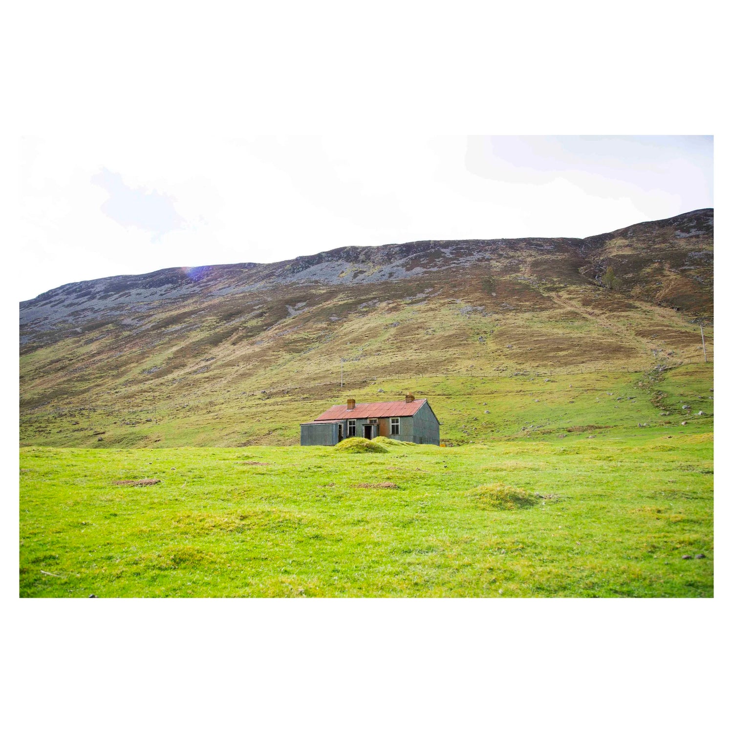Photograph of an abandoned house in the green hills of a glen in Scotland.