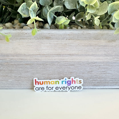 waterproof equality sticker on a wooden surface with greenery in the background