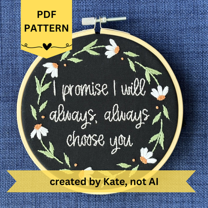PDF pattern created by Kate, not AI. "I promise I will always, always choose you."  Quote hand embroidered in handwriting font in the palest blush pink. Surrounding the text is a floral wreath of white daisies with orange centers. Sewn on black cotton. Framed in a light wood embroidery hoop as wall art.