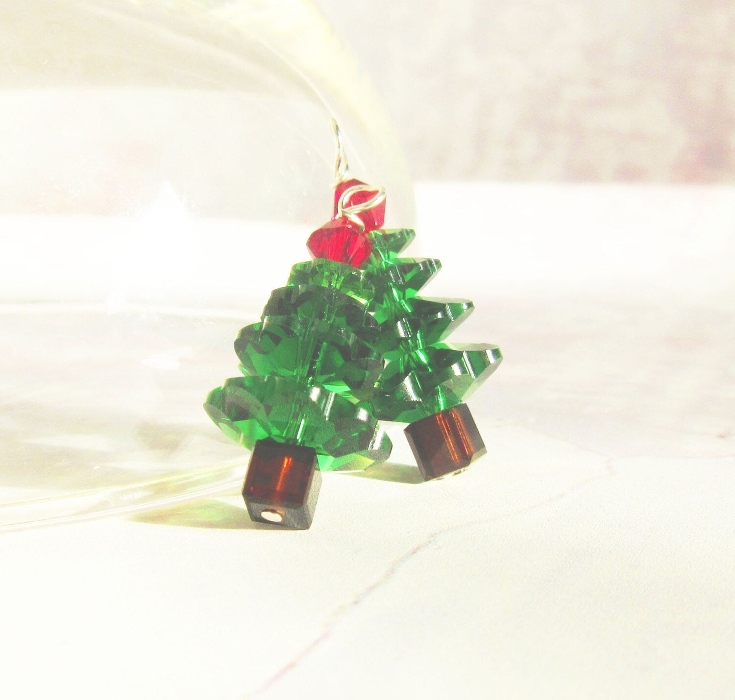 The Crystal Christmas Tree Earrings – Sterling Silver Holiday Jewelry feature festive evergreen shapes with stacked green crystals, brown bases, and a red bead topper, all displayed against a light background.