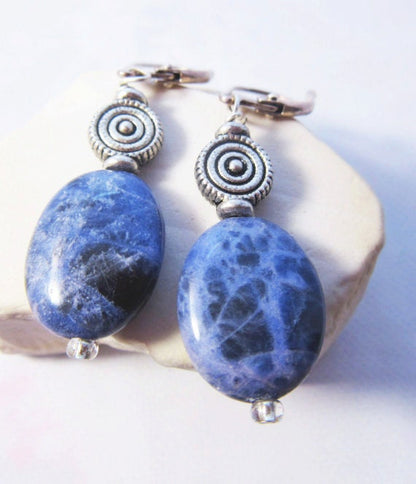 Sodalite earrings - artisan-designed stone and spiral, denim blue earrings. Displayed on a neutral background showcasing the length and lever back style.