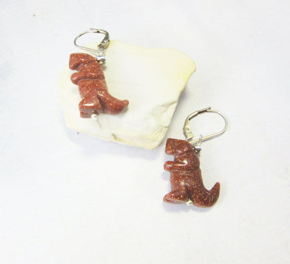 Tyrannosaurus rex earrings featuring intricate carvings and a rust goldstone finish, perfect for a paleontologist gift.