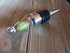 The Color-Changing Wine Stopper: Mood Stone Bottle Topper sits on a rustic wooden surface, displaying its decorative metal design and vibrant handle.