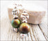 Spring Full Moon Silver Earrings with Color Changing Mood Beads showcase a lunar crescent moon face design and large green-brown mood beads, displayed on light wood with a white stone in the background.