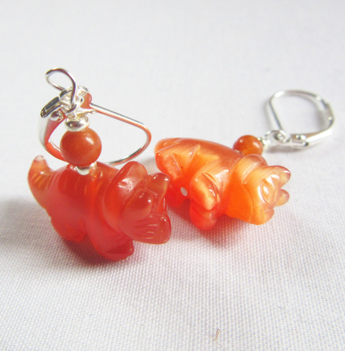 Triceratops earrings displayed on a colorful background - unique dinosaur earrings made from natural stone, a whimsical accessory for any outfit.