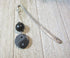 The Yin Yang Bookmark: Natural Stone Accents, Zen Gift Artisan Designed, features a silver metal body with textured handle, black round natural stone bead, and yin-yang charm, displayed on a light wood surface.