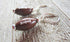 Football Earrings: Sterling Silver Sports Jewelry Gift for the big game, featuring small brown footballs with white stitching on sterling silver hooks, displayed on a textured wooden surface.