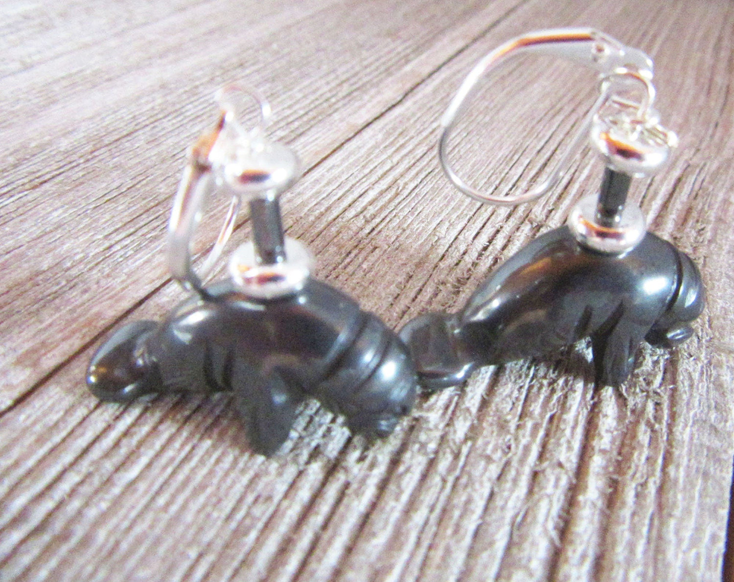 Close-up of Manatee Earrings showing intricate detail of carved hematite black stone, perfect for sea life jewelry enthusiasts.