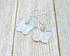 Handcrafted Rose Quartz Butterfly Earrings with sterling silver lever backs are elegantly displayed on a weathered wooden surface, showcasing butterfly-shaped rose quartz pendants and quality silver craftsmanship.