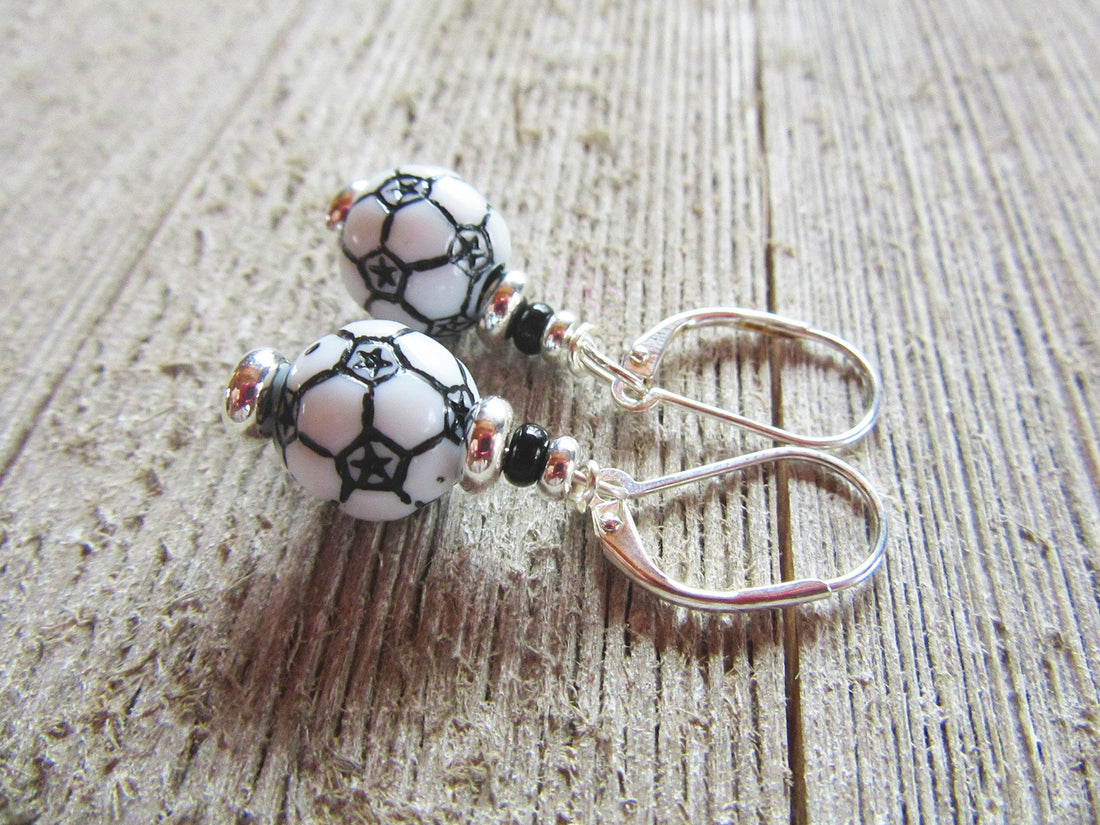 Soccer Ball Lever Back Earrings | Sports Jewelry Gift feature black and white soccer ball beads with silver and black accents, adding a playful sports touch. Perfect for any fan, these earrings are displayed on a wooden surface.