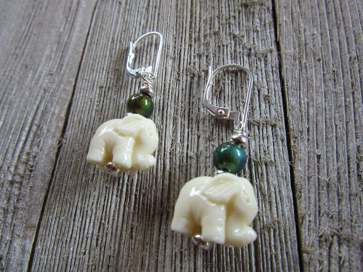 Elephant Earrings – Boho Mood Beads feature cream elephant charms and a sterling silver color change topper bead, displayed on rustic wood. Only one pair available.