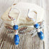 Sodalite Dragonfly Earrings by Gwynstone—handmade nature-inspired jewelry featuring blue stone beads, perfect as a gift for gardeners and wildlife lovers, shown on a light stone surface with a wooden background.