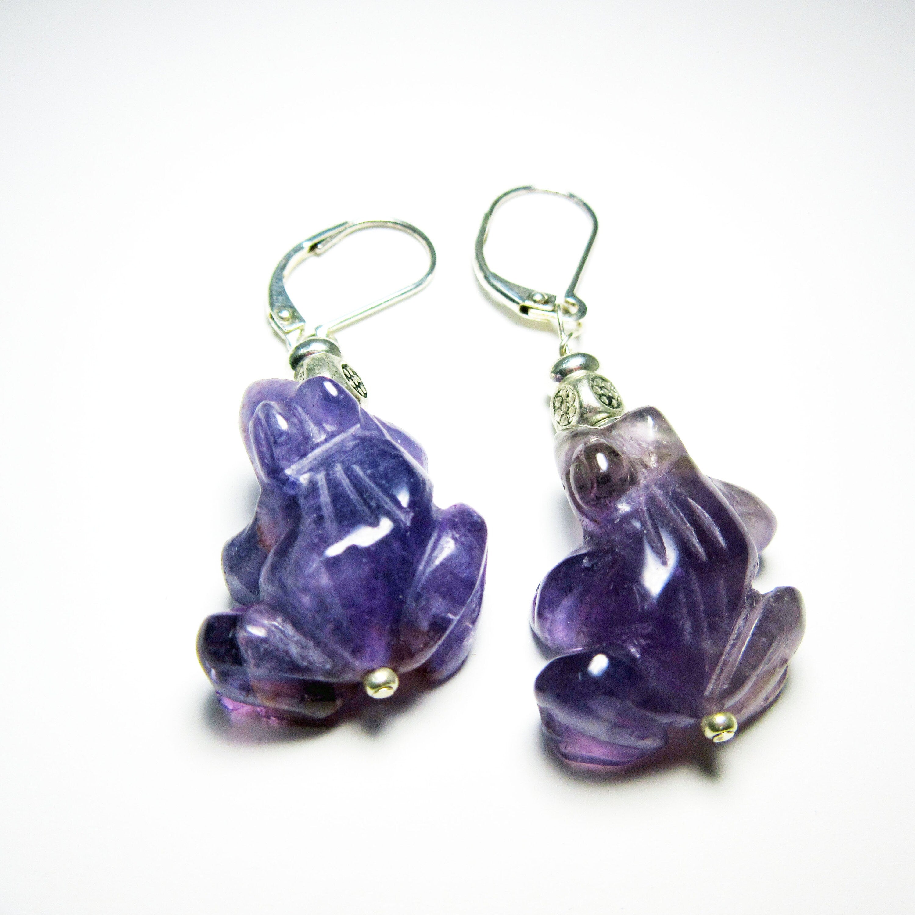 Handcrafted Amethyst Frog Earrings: Animal Jewelry Gift—carved purple gemstone frogs with silver hooks, shown on a white background. A perfect choice for nature-inspired earring lovers and fans of unique, animal-themed jewelry.