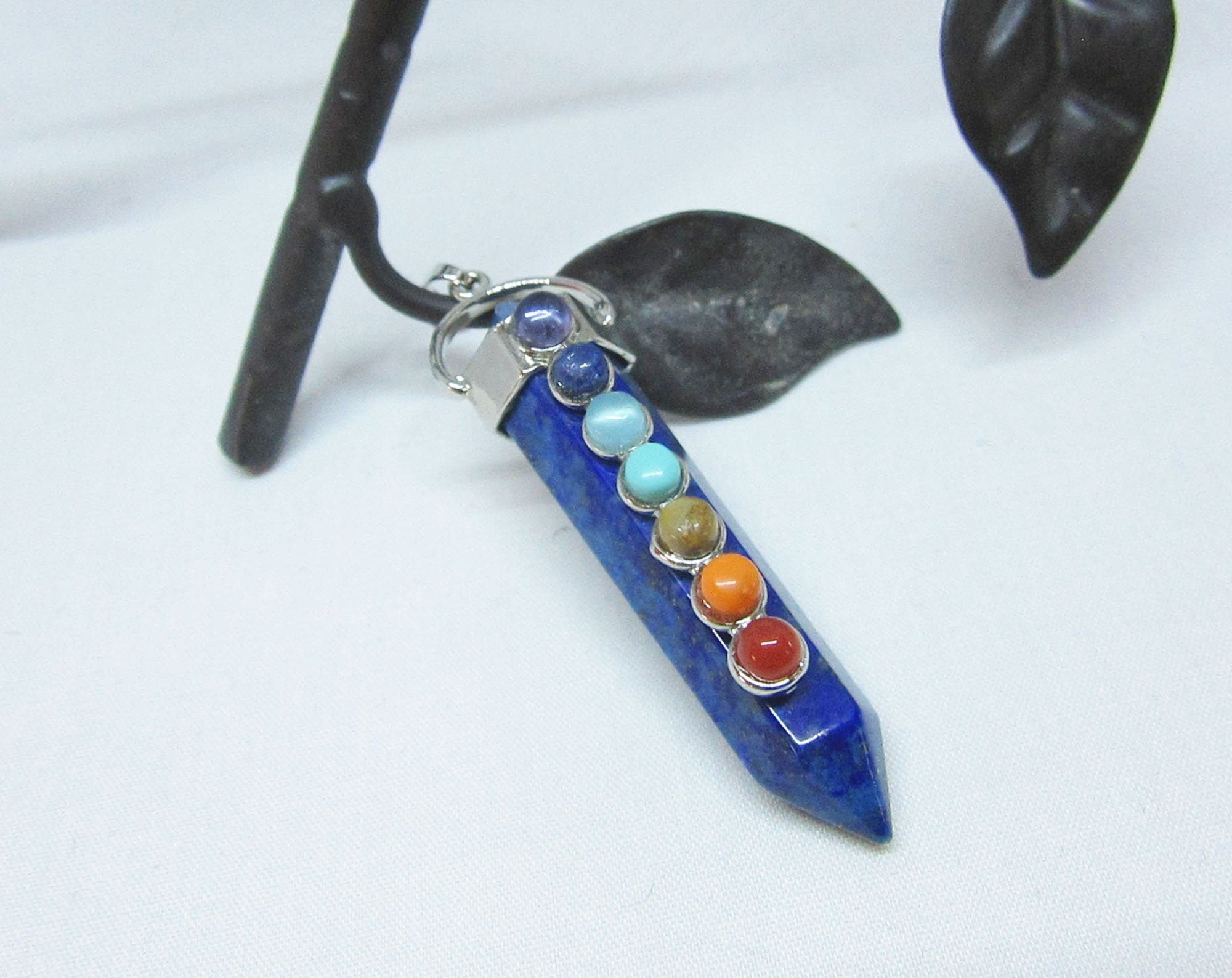 The Chakra Stones Pendant features seven colorful gemstones in a vertical design on a silver chain. This healing gemstone jewelry is ideal for yoga lovers and adds vibrant energy to your style.