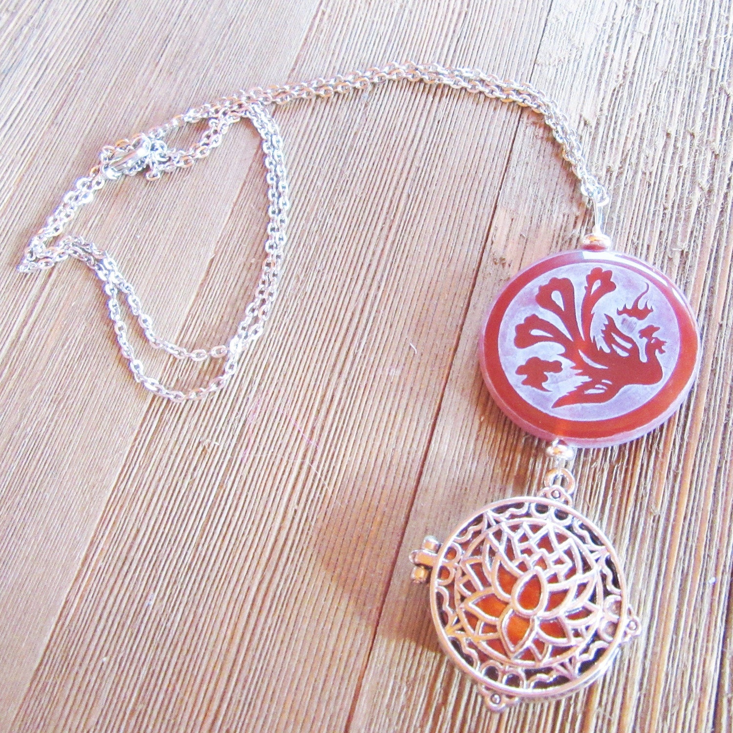 The Lotus Dragon &amp; Peacock Aromatherapy Necklace features a round pendant with color-changing Zen jewelry, displayed on a light wooden surface.