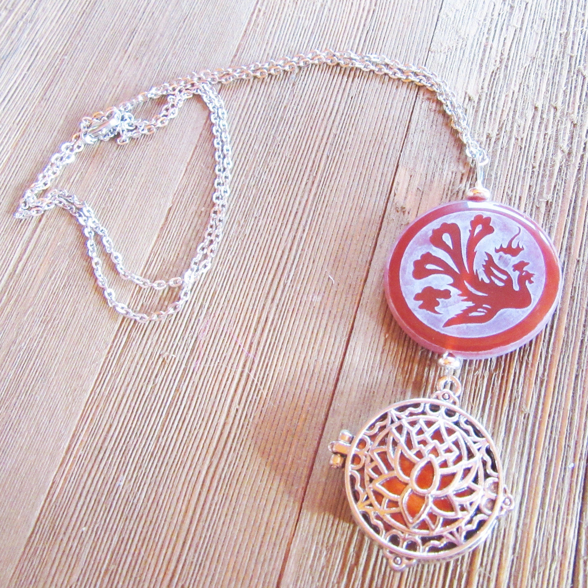 The Lotus Dragon &amp; Peacock Aromatherapy Necklace features a round pendant with color-changing Zen jewelry, displayed on a light wooden surface.