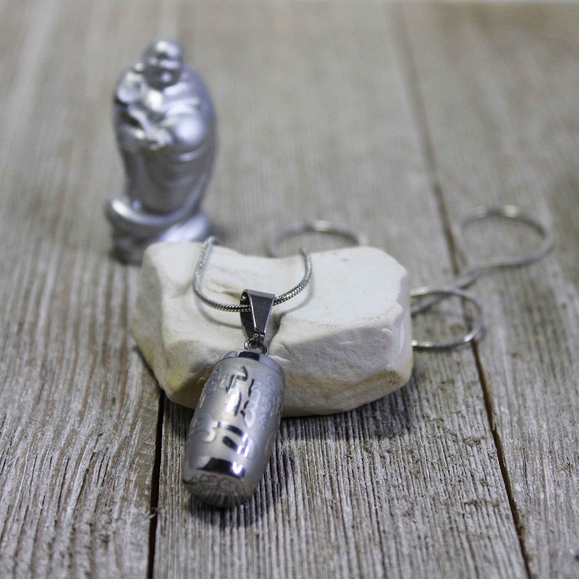 SECRET CHAMBER Reflection Barrel Necklace featuring a stainless steel barrel with an embossed mantra, perfect for holding prayers or essential oils.