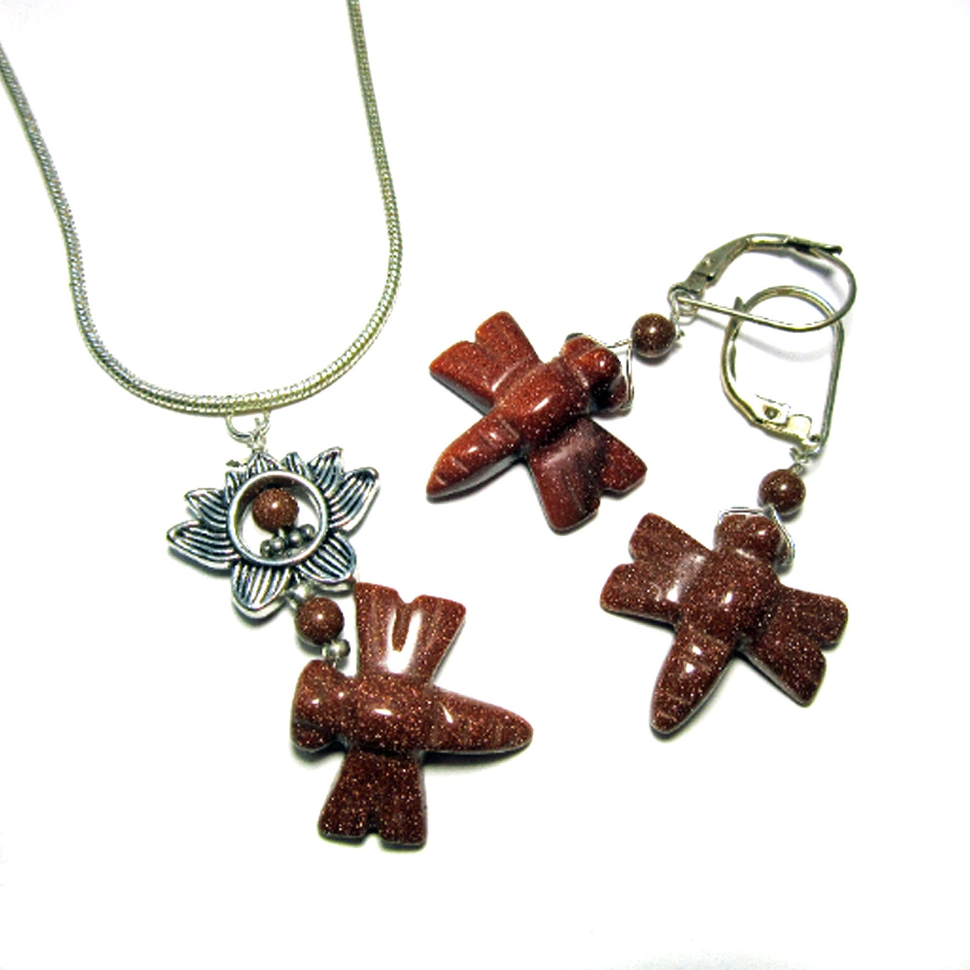 The Dragonfly Goldstone Jewelry Set features a necklace with a flower-shaped pendant and two brown stones, paired with artisan earrings adorned with brown stone birds and round beads, all shown on a white background.
