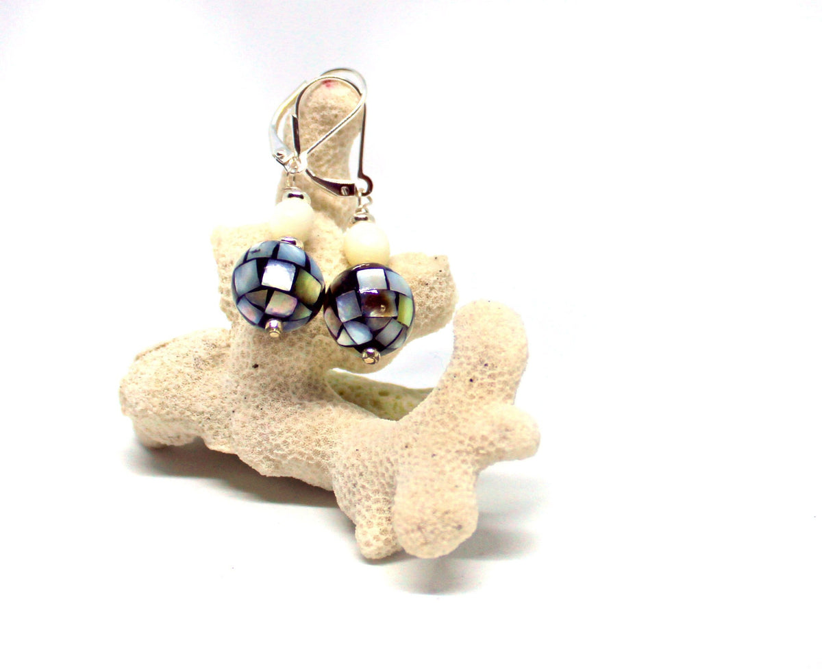 Mother of Pearl Mosaic Orb Earrings: Sterling Silver Lever-Back Dangles featuring blue, silver, and white beads, shown hanging on light-colored coral with a white background.