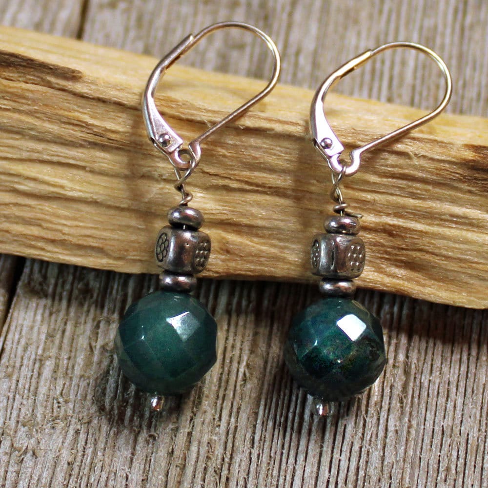 Teal Jasper Earrings: Sterling Silver Artisan Sacred Geometry Jewelry featuring faceted dark green-blue jasper beads and metal accents, displayed on wood over a rustic wooden surface.