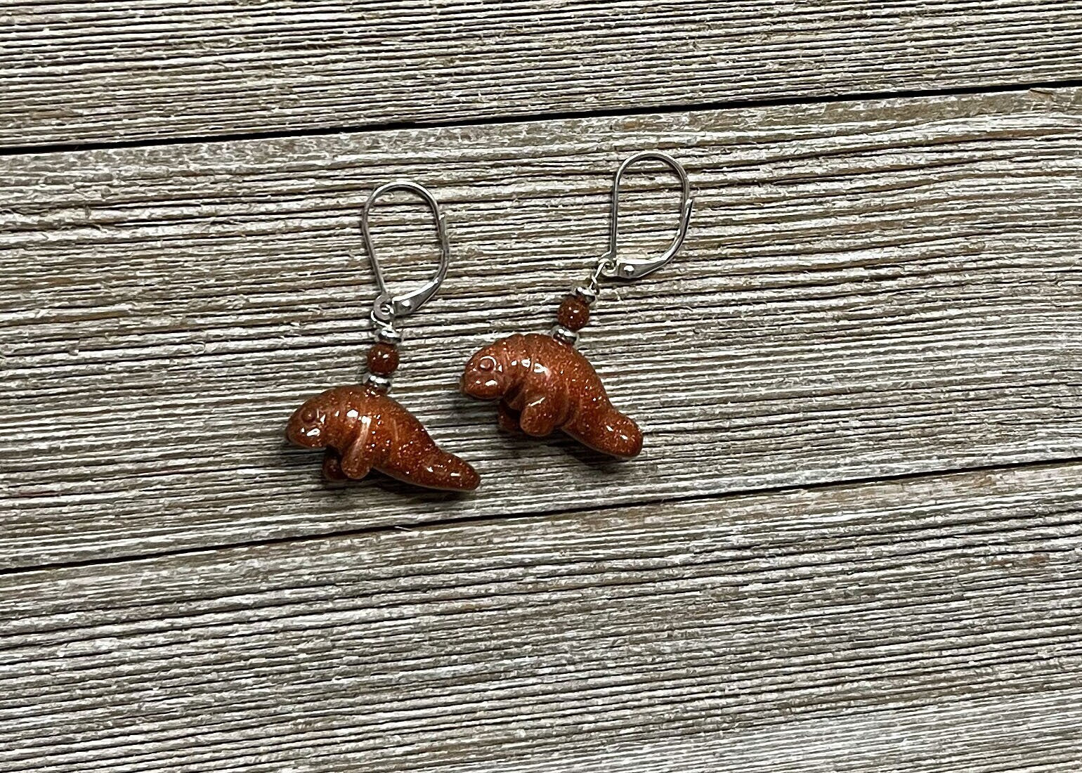 Close-up of Manatee Earrings showing intricate details of the artisan-crafted jewelry, made from shimmering blue and orange goldstone.