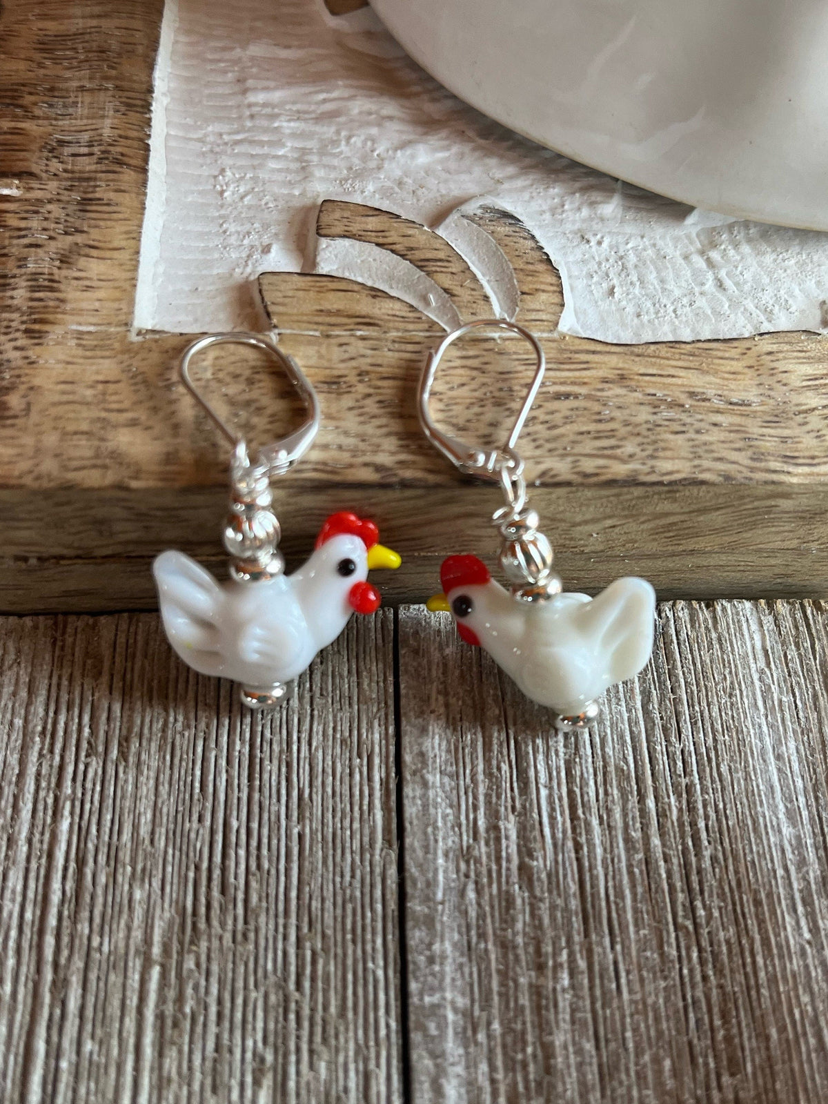 Hen Earrings Gift that is egg strOrdinary - white lamp work glass chicken jewelry displayed on a rustic surface.