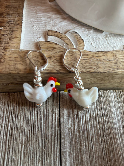 Hen Earrings Gift that is egg strOrdinary - white lamp work glass chicken jewelry displayed on a rustic surface.